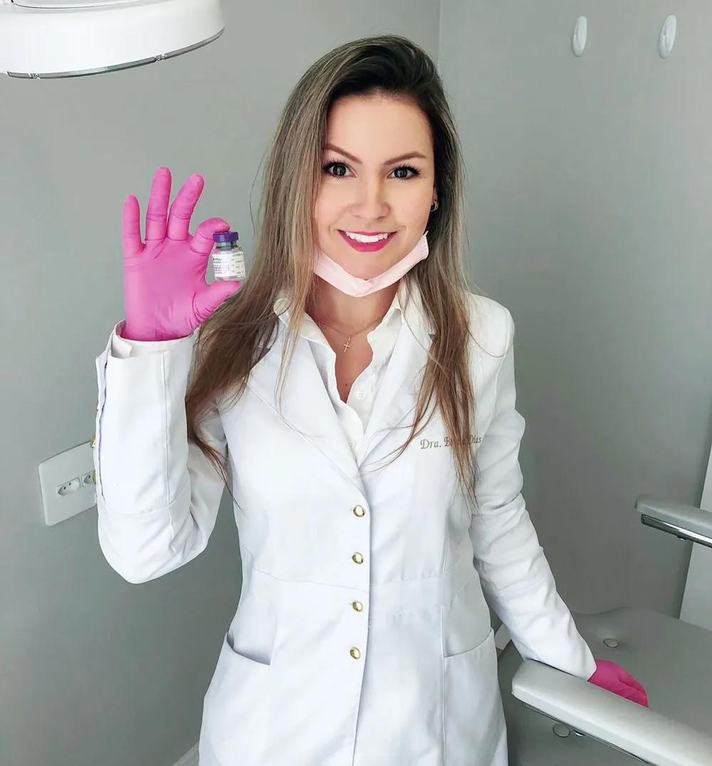 Dra. Bruna Dias Amaral no consultório, de jaleco branco